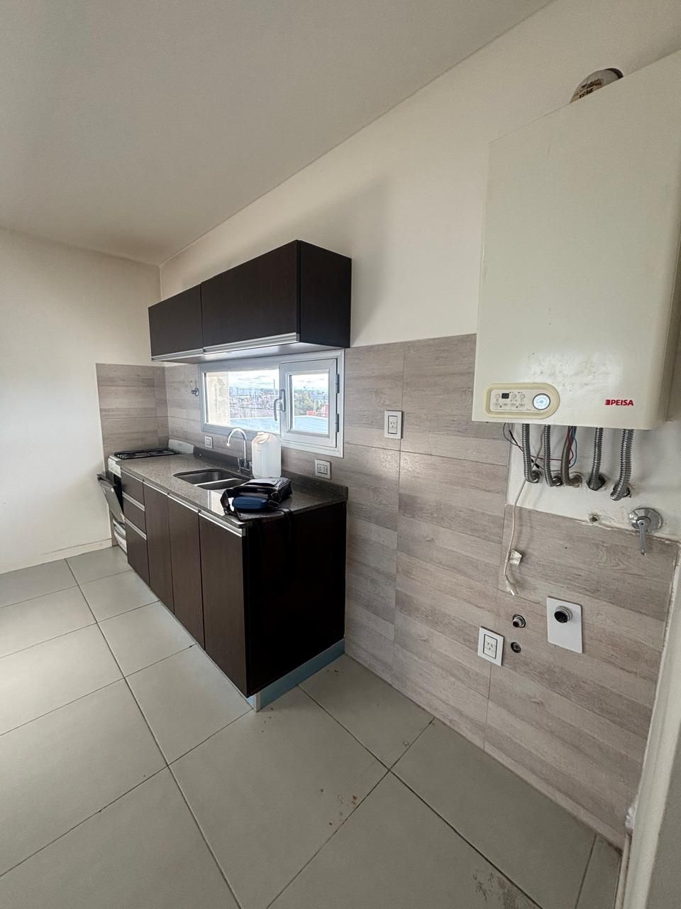 Cocina con mesada de granito, alacenas oscuras y ventana