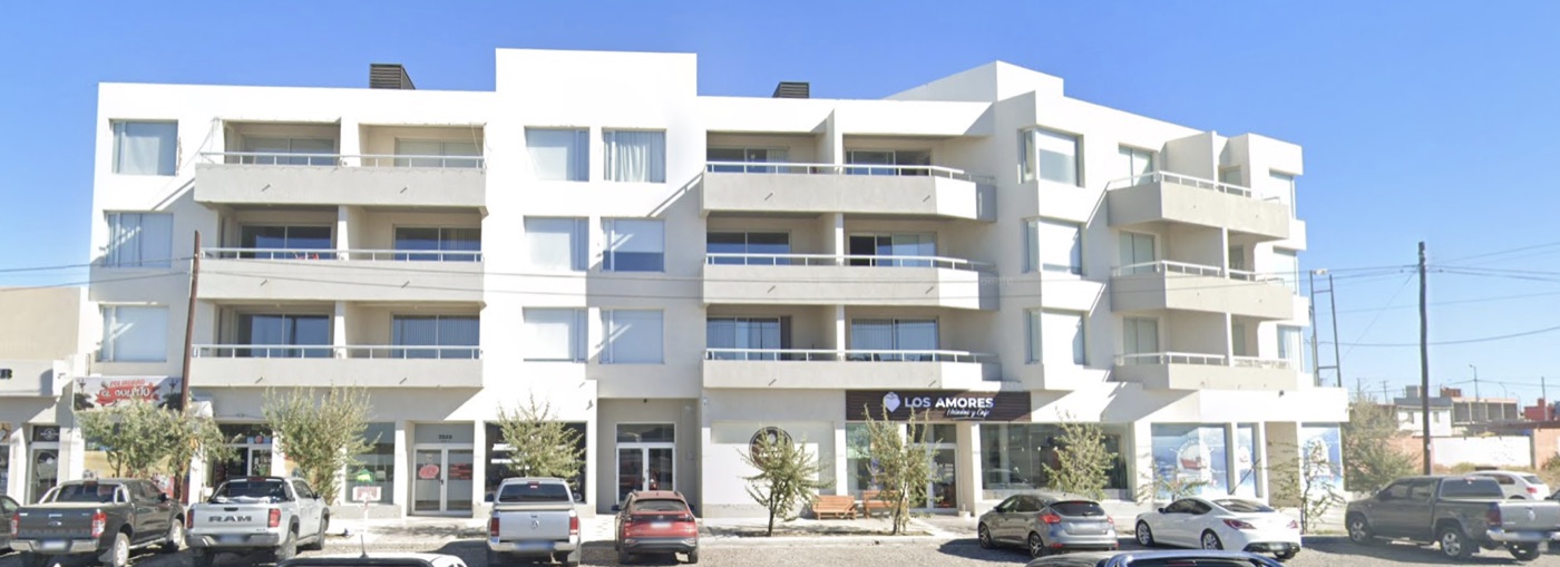 Frente del edificio: cuatro pisos con balcones corridos y locales comerciales en planta baja
